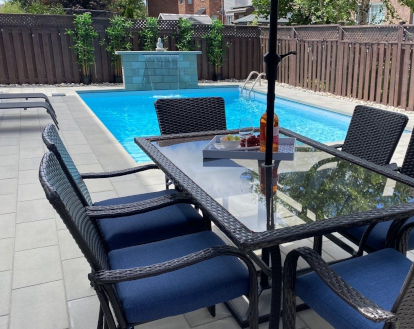Patio surrounding a pool consisting of large light grey rectangular paver stones in a linear pattern exemplifying Interlocking Patio Stone work in a large area